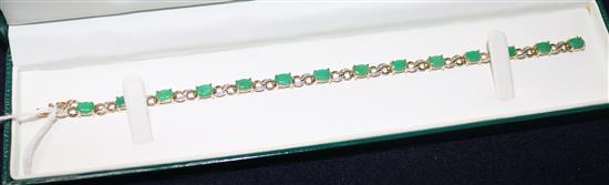 A modern 9ct gold and emerald set line bracelet, 7.5in.